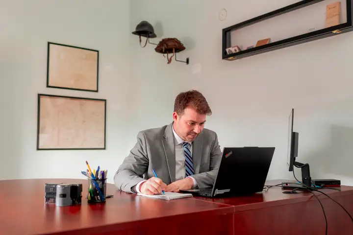 Curran Tompkins writing at his desk in the firm's Moncton office