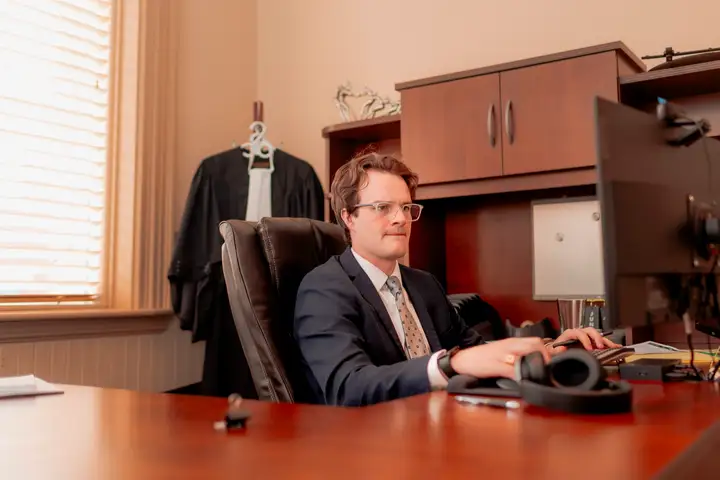 Jantzen Losier at his desk, his barrister's robes hanging behind him