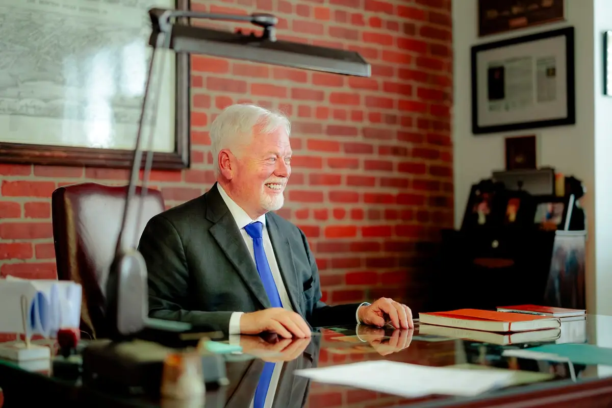 Michael Murphy, K.C., smiling at his desk in front of a brick wall