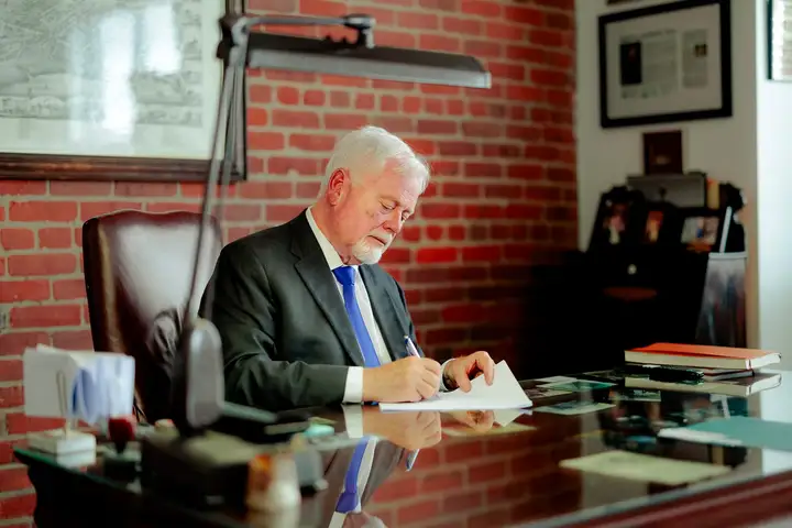 Michael Murphy, K.C. signing a document at his desk in Moncton